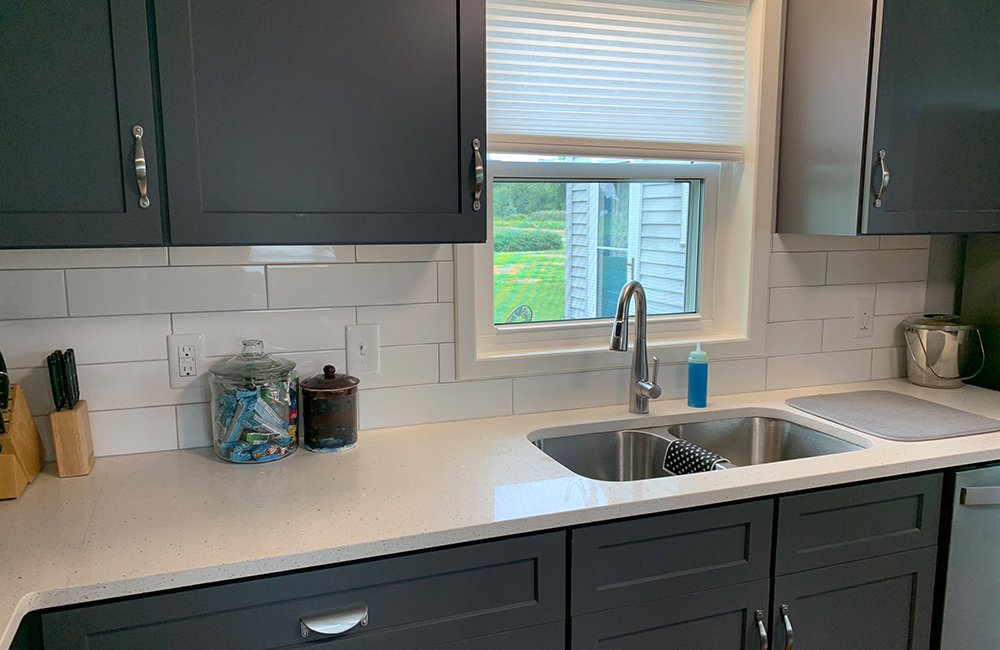 White glossy subway tile backsplash installed by Big Bob’s Flooring Outlet brightens and refreshes this kitchen.